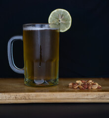 beer chopp with a slice of lemon and peanuts on a wooden surface and a black background