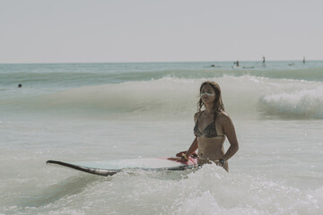 Closeup shot of a beautiful young lady with a surfing board in the water