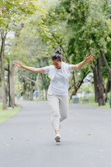 Fototapeta na wymiar asian woman senior sportswear cheerful running and arms outstretched. joyful exercise in garden. happy mature healthy lifestyle.