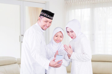 Fototapeta premium Happy family congratulate gesture Eid on cellphone