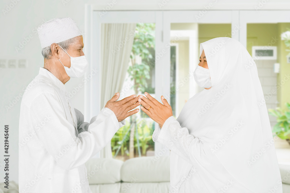 Wall mural Muslim old couple in mask forgiving to each other