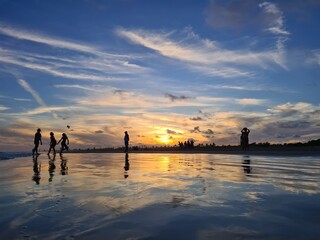 Silhuetas de pessoas em um por do sol na praia