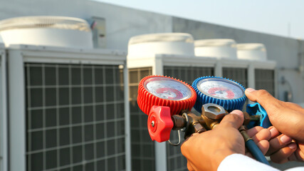 Close up hand of engineer using measuring manifold gauge for filling industrial factory air...
