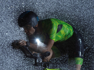 triathlon athlete riding bike on rainy night