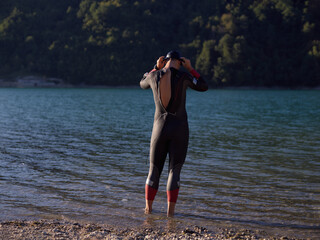authentic triathlon athlete getting ready for swimming training on lake