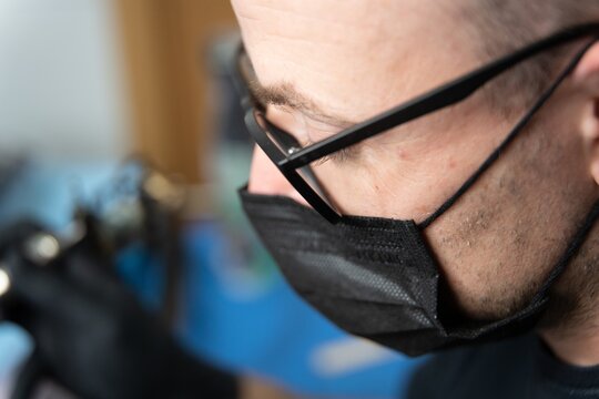 Extreme Closeup Shot Of A Tattoo Artist With Face Mask Creating A Tattoo