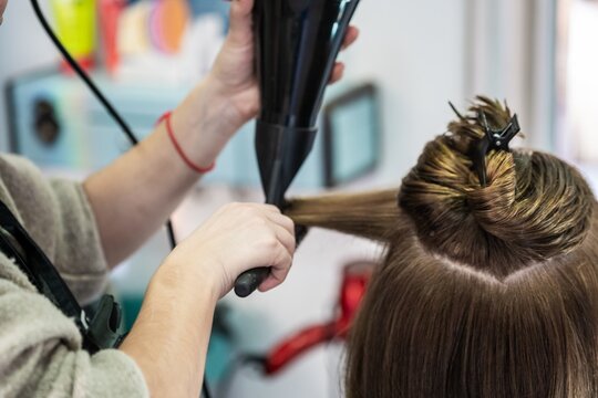 Closeup shot of a hairdresser blow drying a woman's short hair in a beauty salon