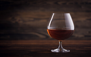 Glass of cognac or brandy on natural wooden background. Glass of whiskey. Alcohol drink on Bar counter in the restaurant. Macro close-up with copy space. 
