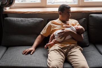 Man holding his newborn baby and looking away while spending time together