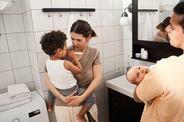 Man holding at the hands his newborn son at the bathroom