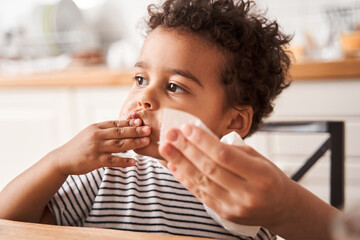 Boy holding his bread with peanut butter while eating it with appetite