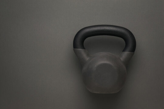 Sports kettlebell covered with rubber on a dark gray background.