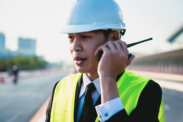 Asian manager engineer with hardhat,work outside industry,use digital tablet,radio communication control,with walkie talkie,work survey building construction factory site,business working and industry