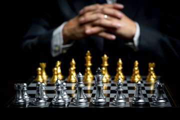 Business man with clapped hands planning strategy with chess figures on chessboard. Business strategy planing concept
