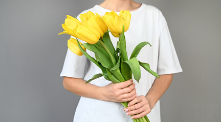 Woman holds tulips in her hands. Florist girl gathered a bouquet. Beautiful yellow flowers.