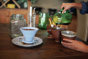 barista preparing brewing coffee with coffee maker and drip kettle.