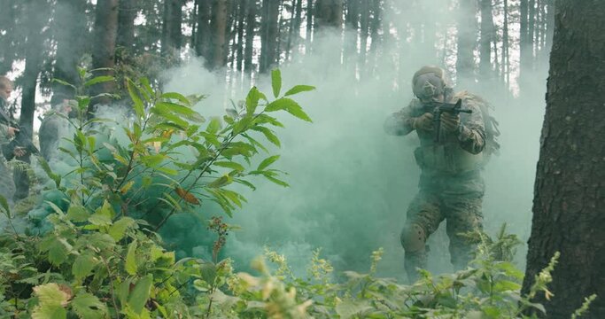 Soldiers running millitary action in dense forest with smoke in backgorund, army conducting action in forest