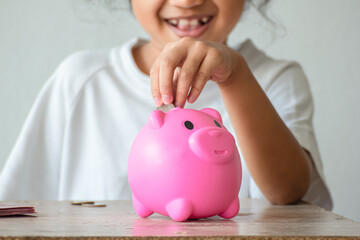 Obraz na płótnie Canvas Little girl saving money in the pink pig savings