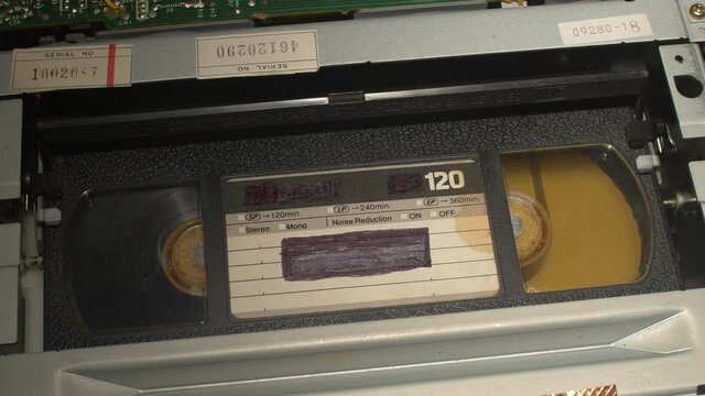 Inserting a VHS tape in a VCR overhead with cover open