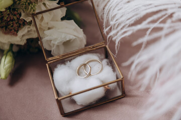 wedding gold rings in a glass box lie next to a wedding bouquet  with austom. aesthetics and details of the wedding