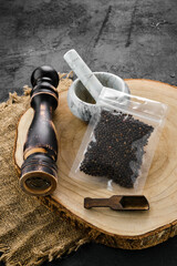 Wooden cross section with peppercorn in plastic package and mortar and mill