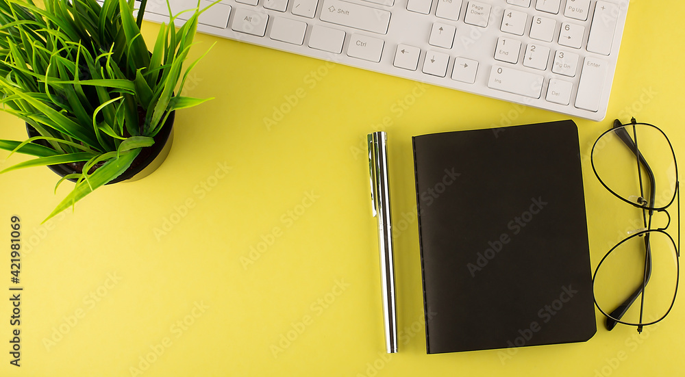 Poster view from above on white office table with notepad on yellow background