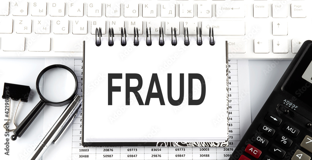 Poster white notebook with text fraud on white keyboard with calculator,magnifier and pen