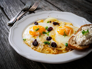 Continental breakfast - sunny side up eggs with onion and parmesan on wooden background