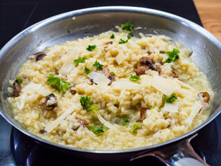 Risotto with white mushrooms and parmesan cooking in frying pan
