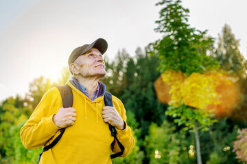 Naklejka premium Senior hiker in cap and with rucksack looks in mountain top.