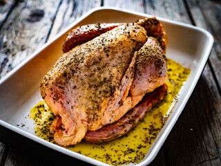 Whole fresh raw chicken on wooden table prepared to roast
