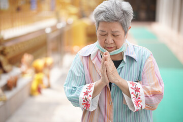 old asian senior woman traveler tourist praying at buddhist temple.