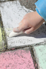 Kind malt mit Malkreide auf Pflastersteinen