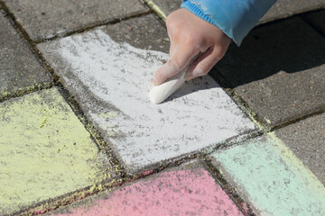 Kind malt mit Malkreide auf Pflastersteinen
