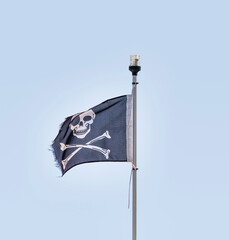 Pirate flag with a skull and two crossed bones in the wind,