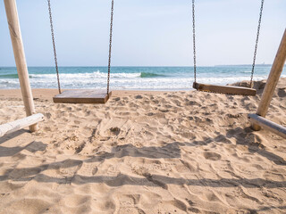 Summer vacation landscape with a wooden swing on the beach. Sunny clear day at the beach.