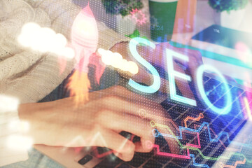 Obraz premium Double exposure of woman hands working on computer and seo hologram drawing. internet search concept.