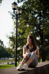 a beautiful Asian girl sits on the parapet against a background of green foliage
