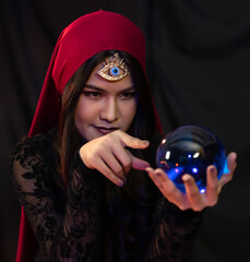 Asian fortune teller looking at crystal ball