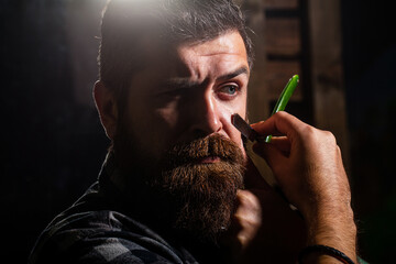 Man in barbershop. Handsome bearded hairdresser is holding a straight razor while barbershop....