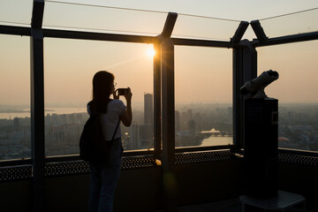 the silhouette of a girl standing on the observation deck and looking at the sunset