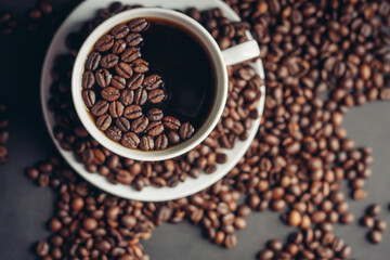 coffee beans on a gray background and a hot aromatic drink on a saucer top view