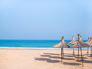 Summer landscape with straw umbrellas on the beach in Mangalia or Mamaia. Beach at the Black Sea in...