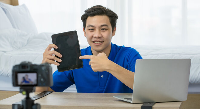Asian technology blogger showing tablet to audience