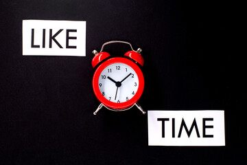 text LIKE TIME on white paper and a red alarm clock on a black background.Social media concept.