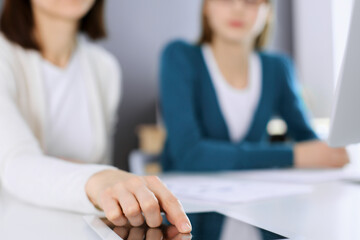 Businesswoman pointing at tablet computer screen while giving presentation to her female colleague....
