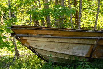 Old abandoned rusty boat in the middle of a forest with green trees at background. Abandoned submarine base at sunny summer day. Selective focus.