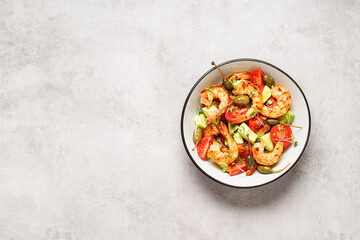 Easy grilled shrimp avocado salad with cherry tomatoes, capers and microgreens. Gray background. Top view. Space for text.