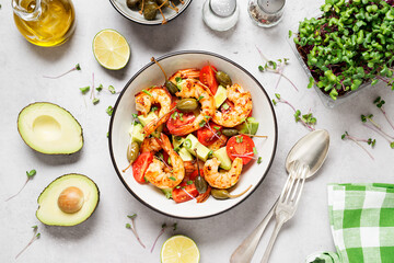 Easy grilled shrimp avocado salad with cherry tomatoes, capers and microgreens. Gray background. Top view. 