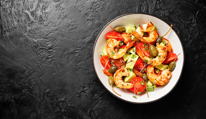 Easy grilled shrimp avocado salad with cherry tomatoes, capers and microgreens. Black background. Top view. Space for text.